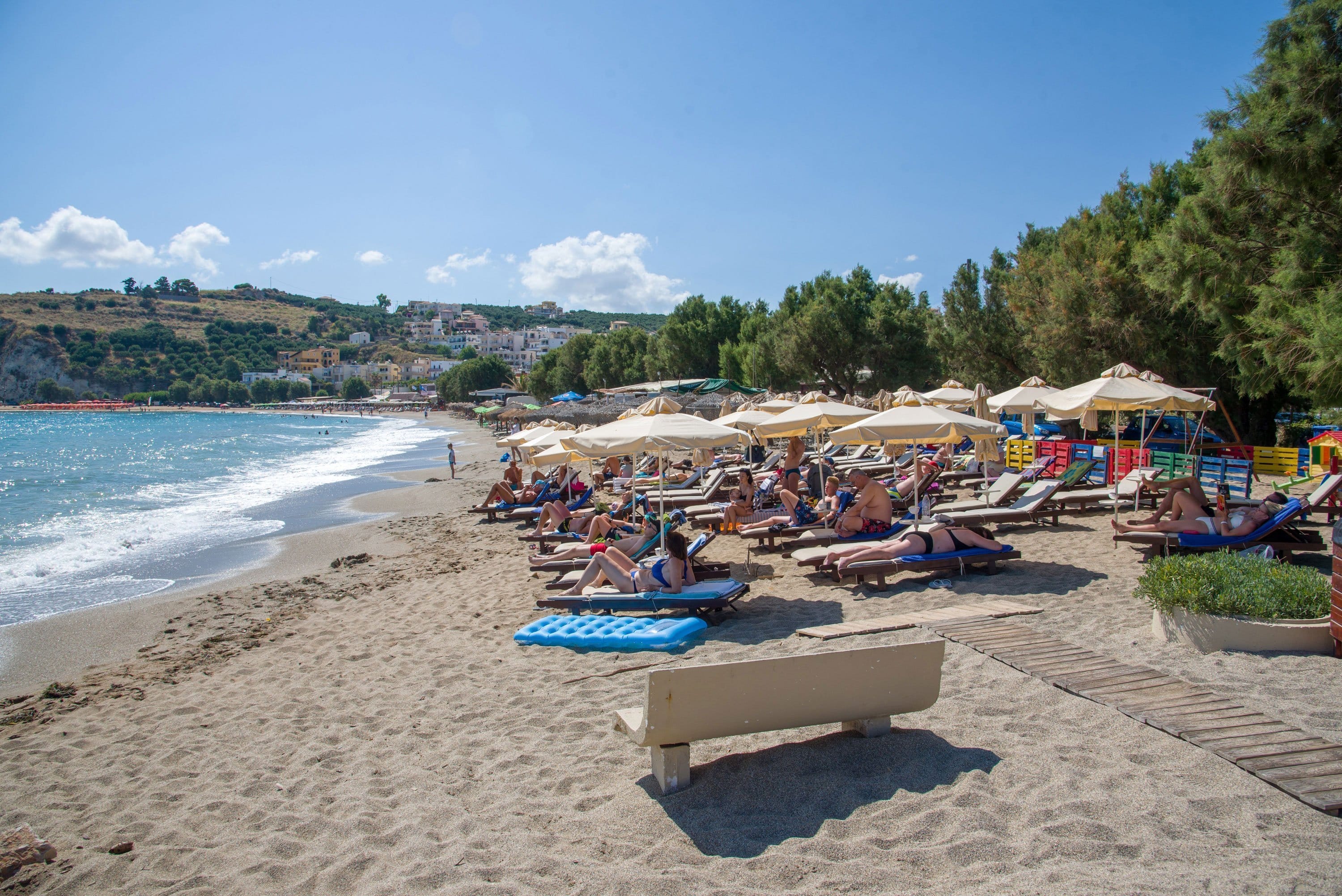 a beach with many people and umbrellas