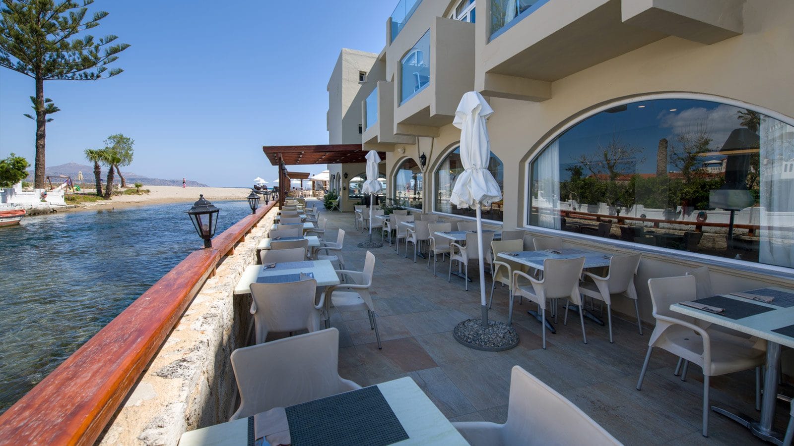 a patio with tables and chairs next to a body of water