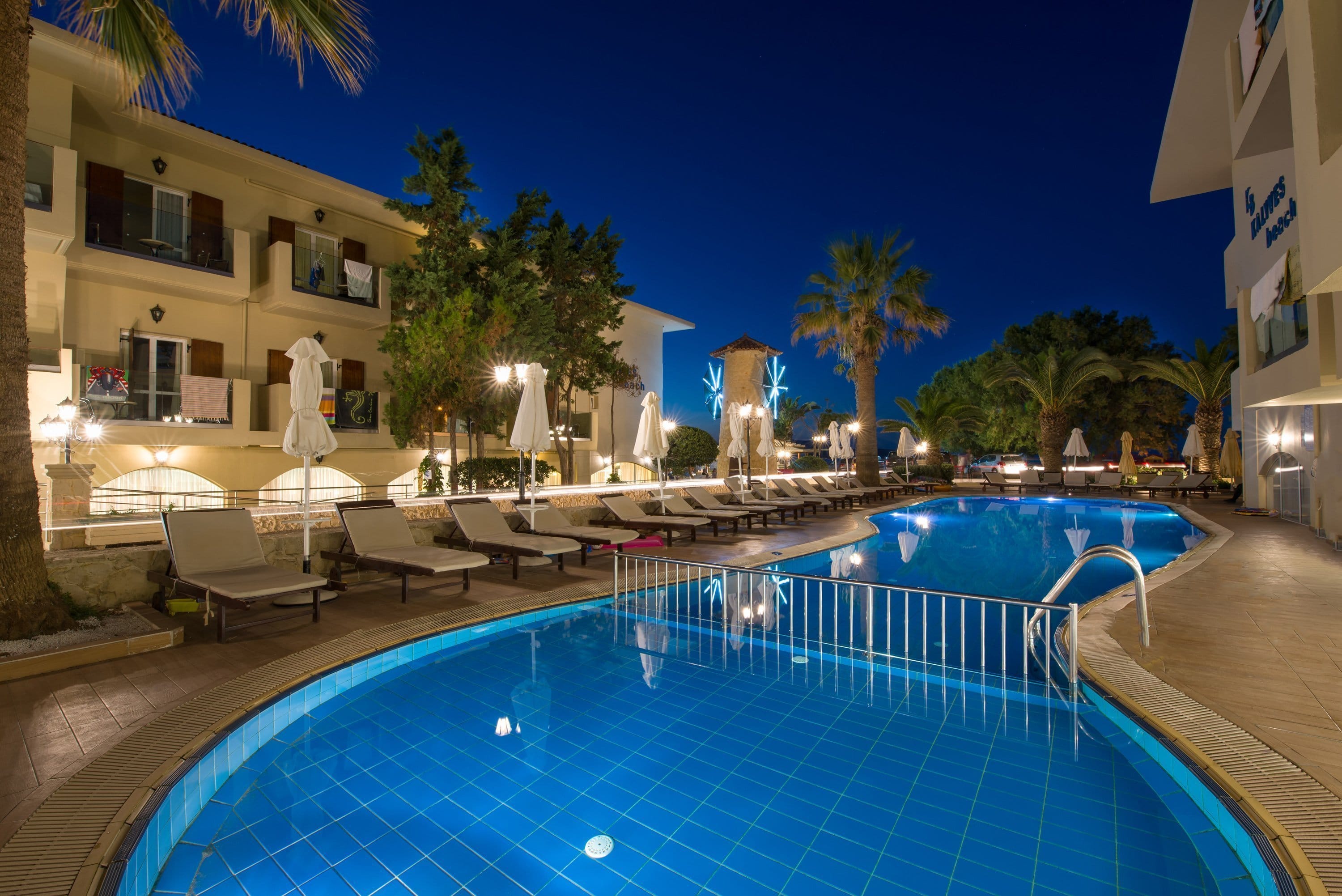 a pool with chairs and umbrellas next to a building