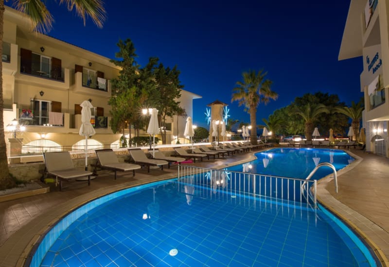 a pool with chairs and umbrellas next to a building