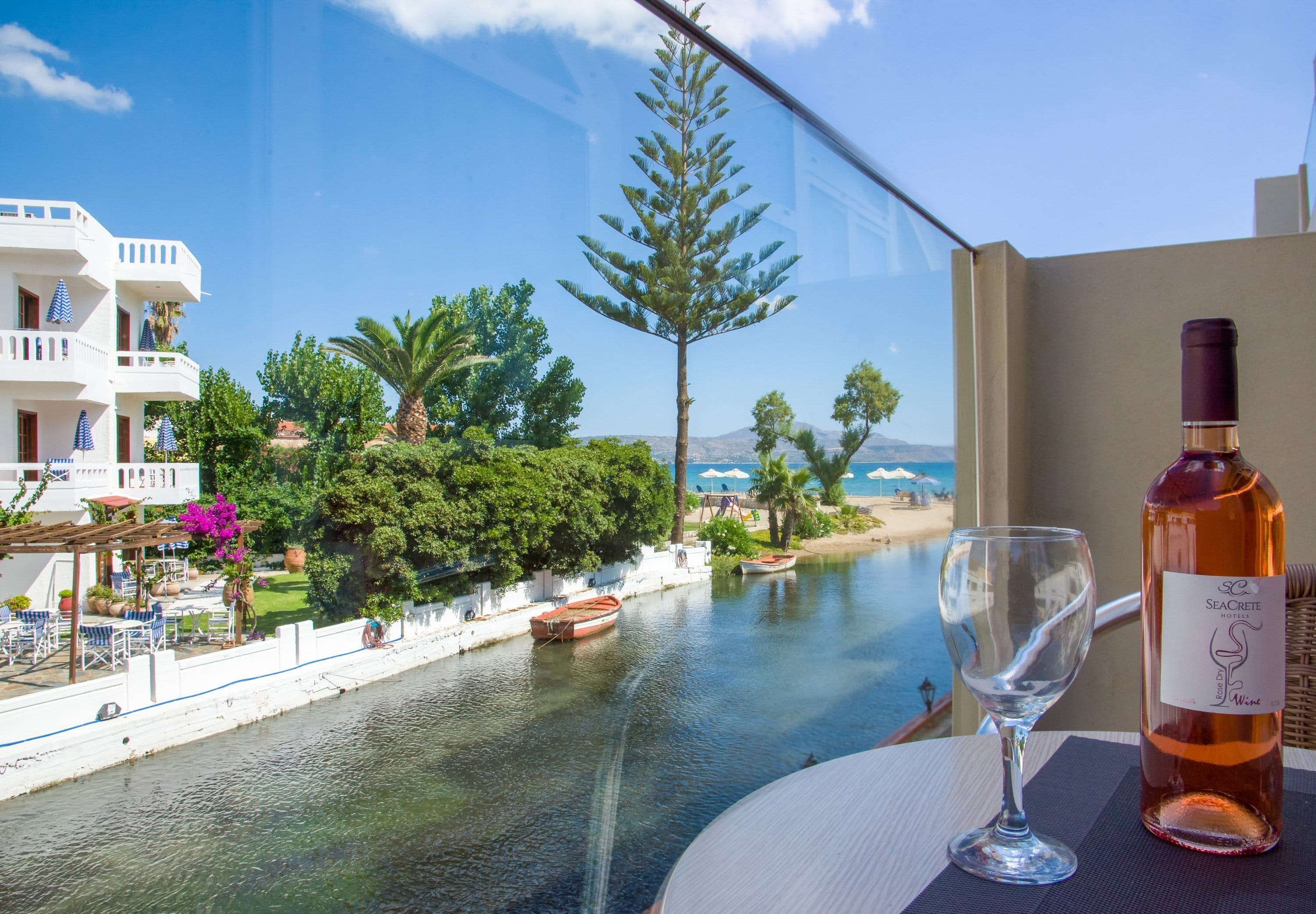 a bottle of wine and a glass of wine on a table by a pool