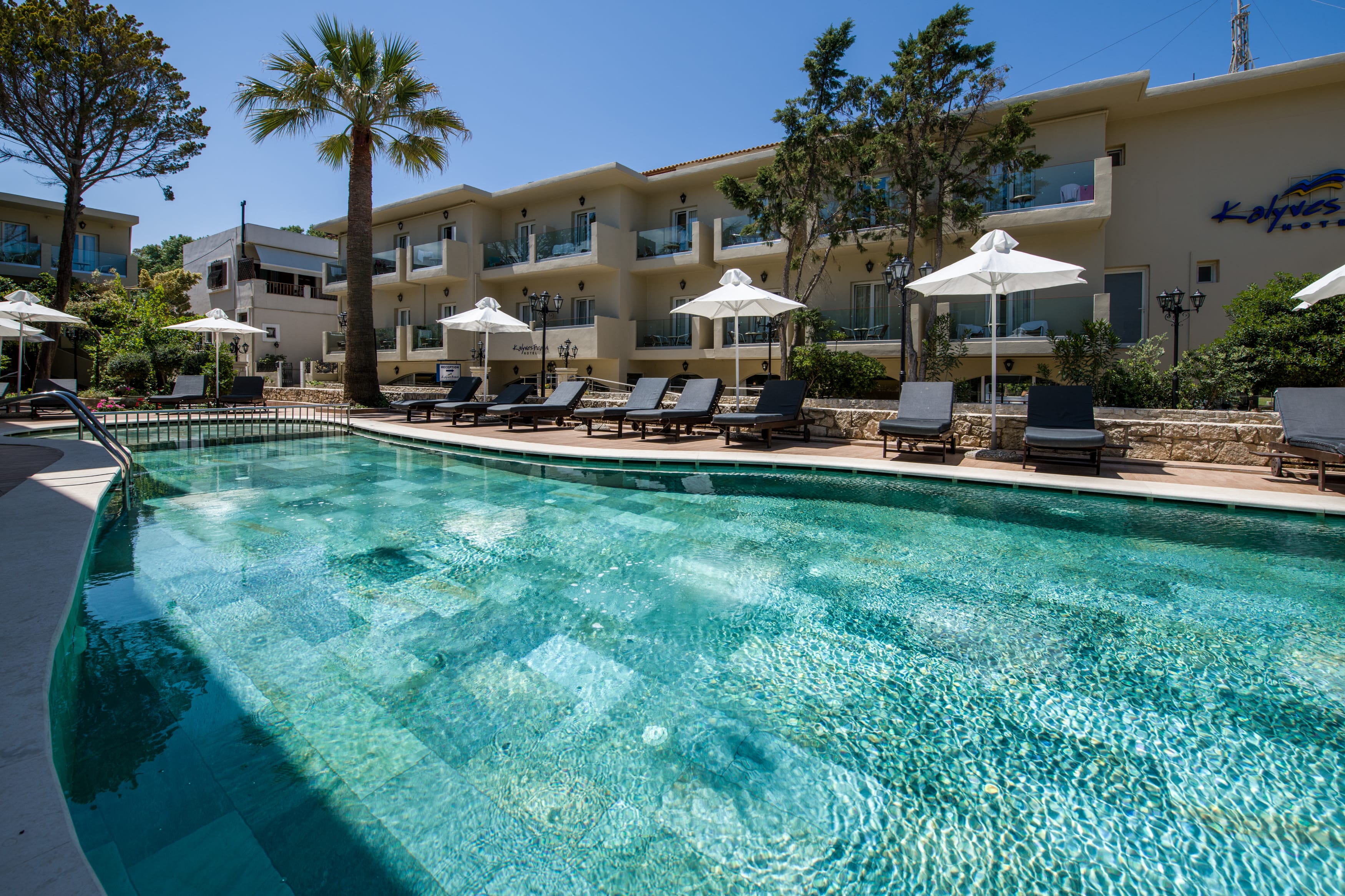 a pool with chairs and umbrellas by a building