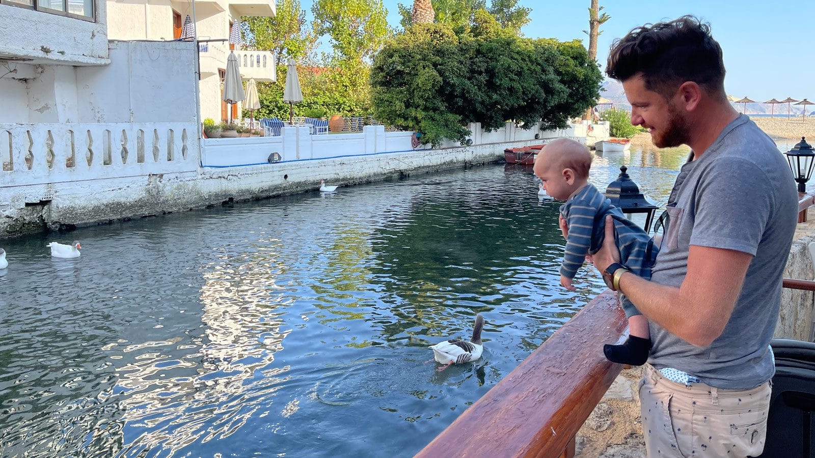 a man holding a baby by a body of water