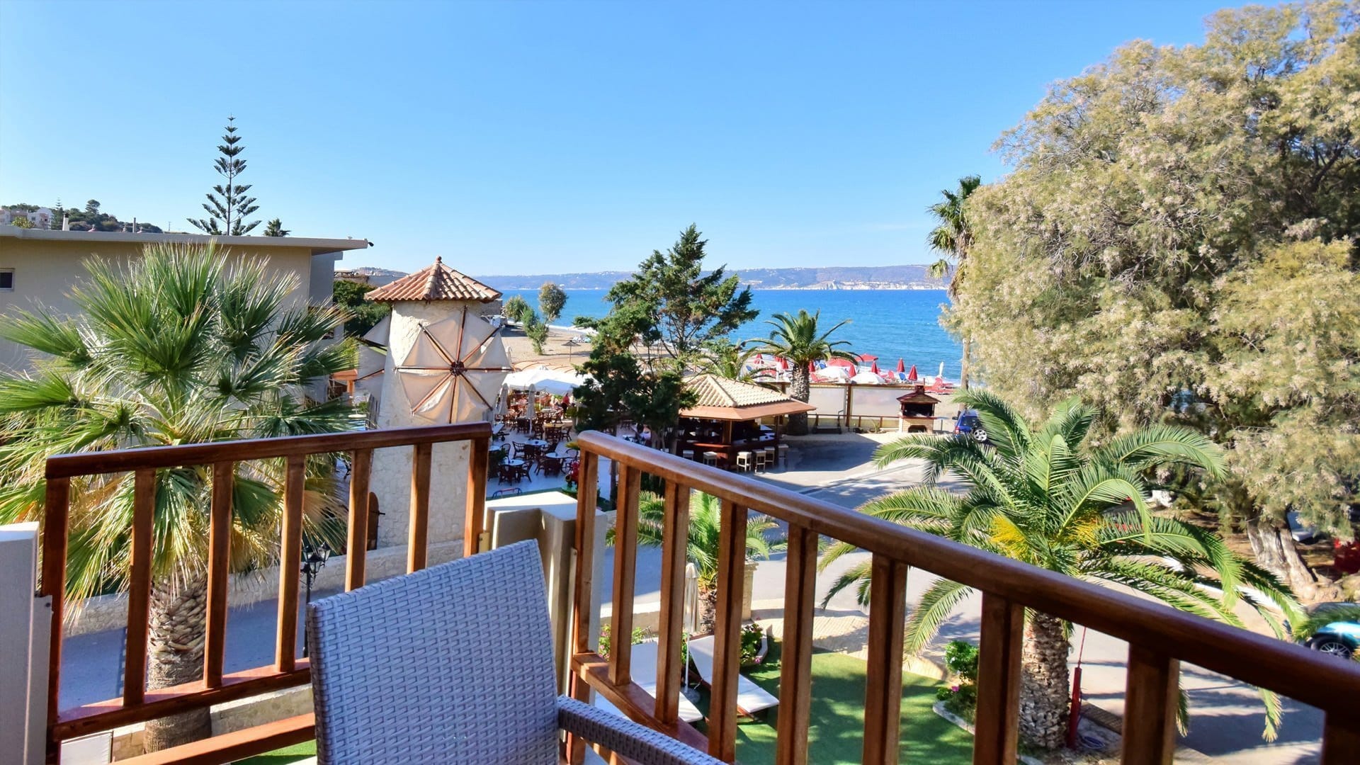 a deck with chairs and tables and trees by the water