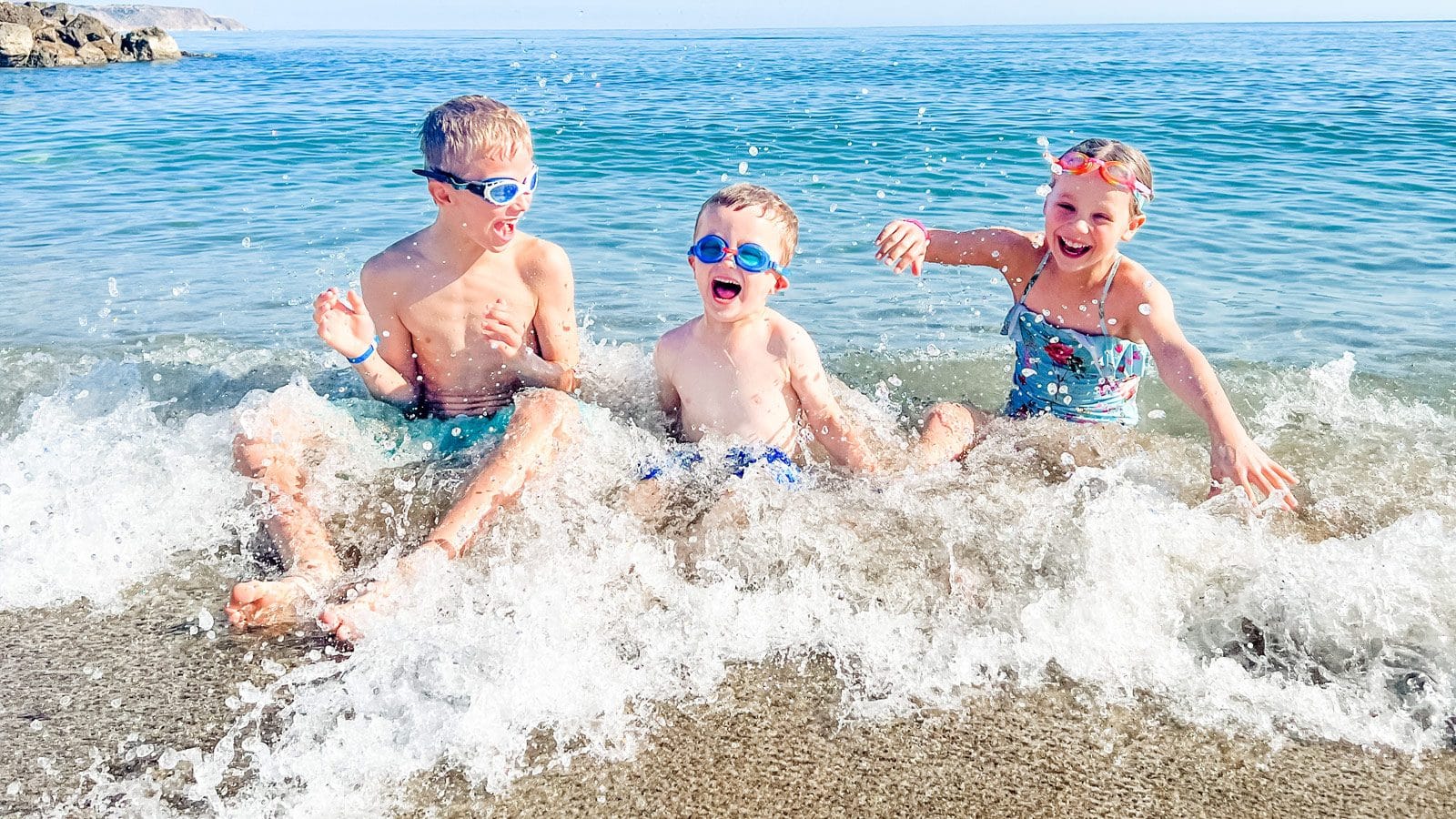 a group of kids playing in the water at the beach