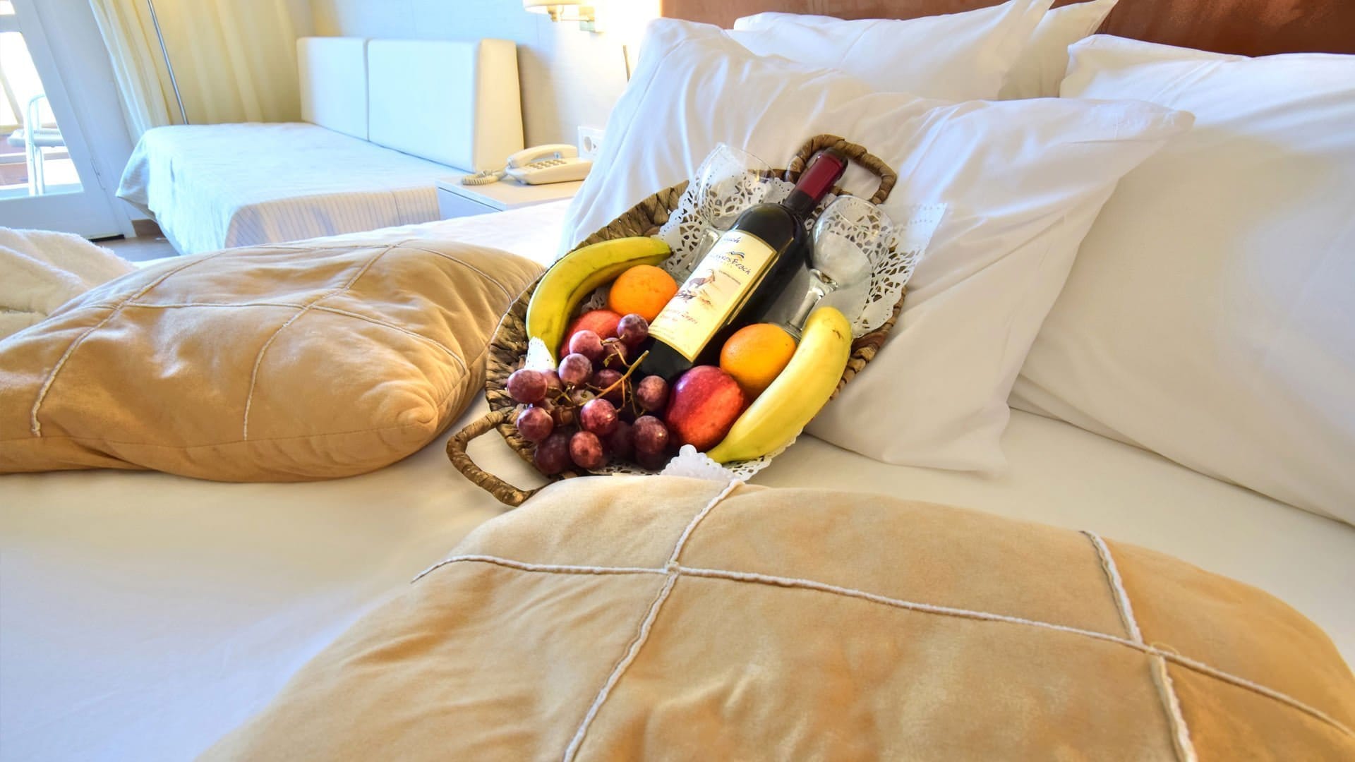 a basket of grapes and a bottle of wine on a bed