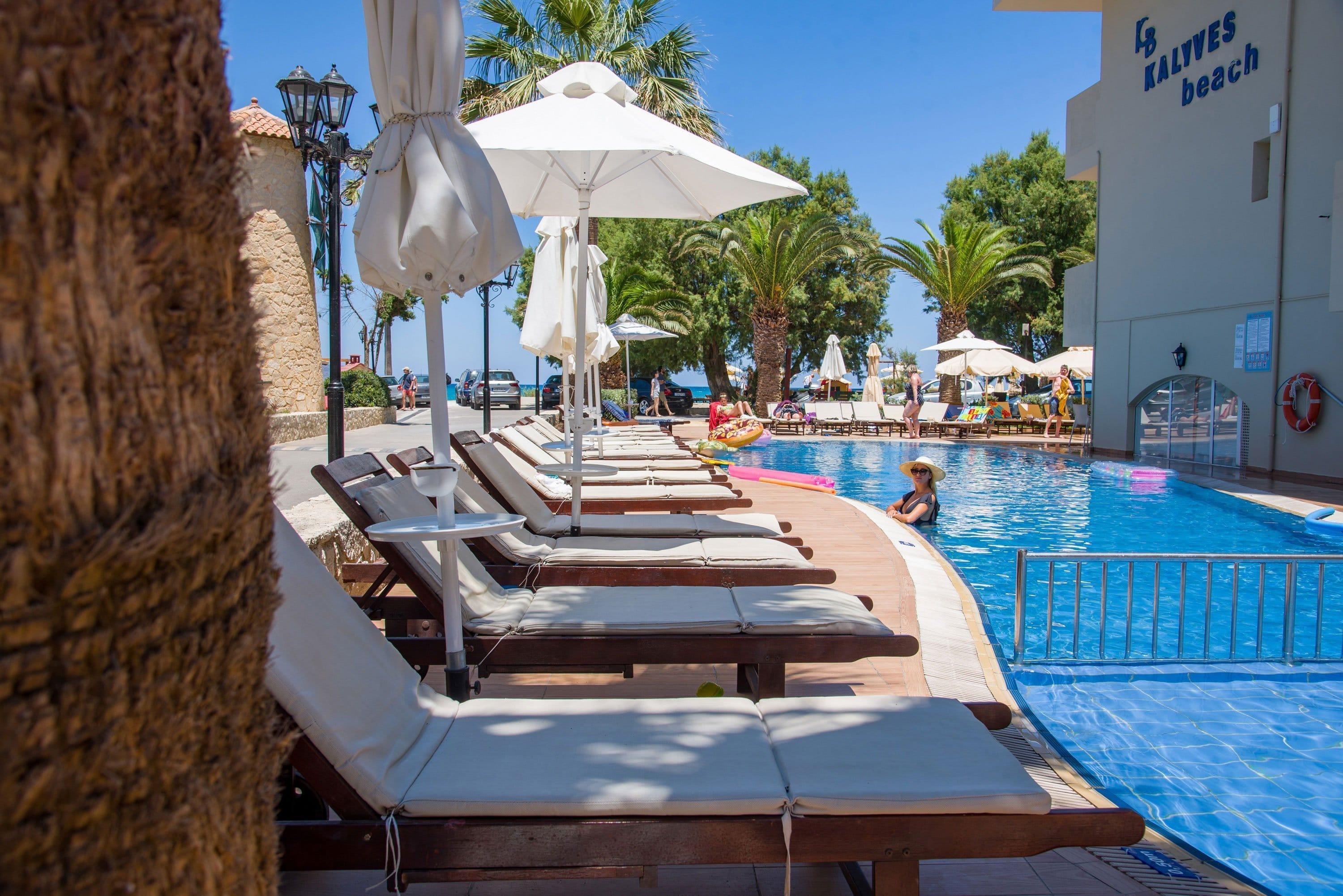 a pool with lounge chairs and umbrellas by a building