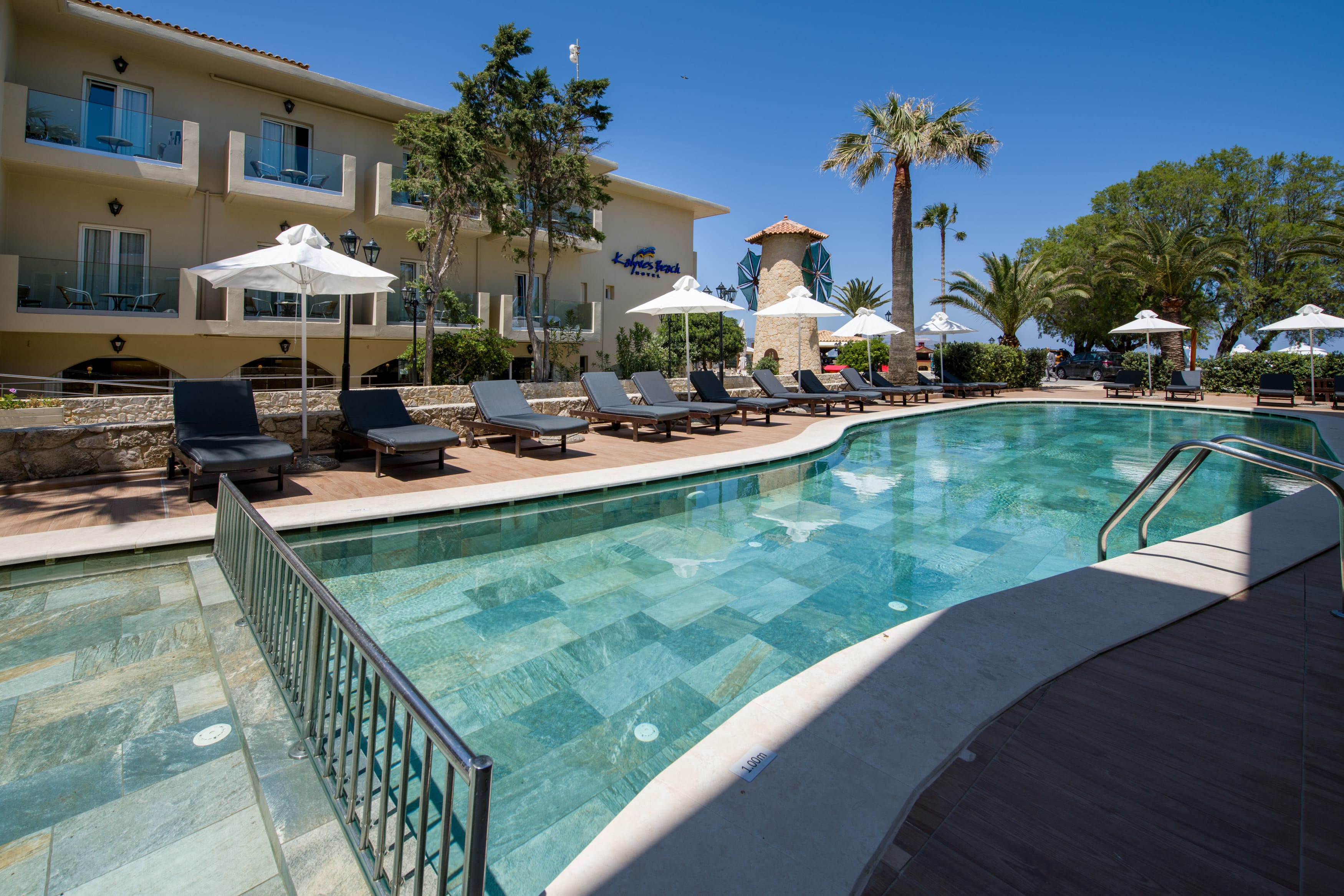a pool with chairs and umbrellas by a building