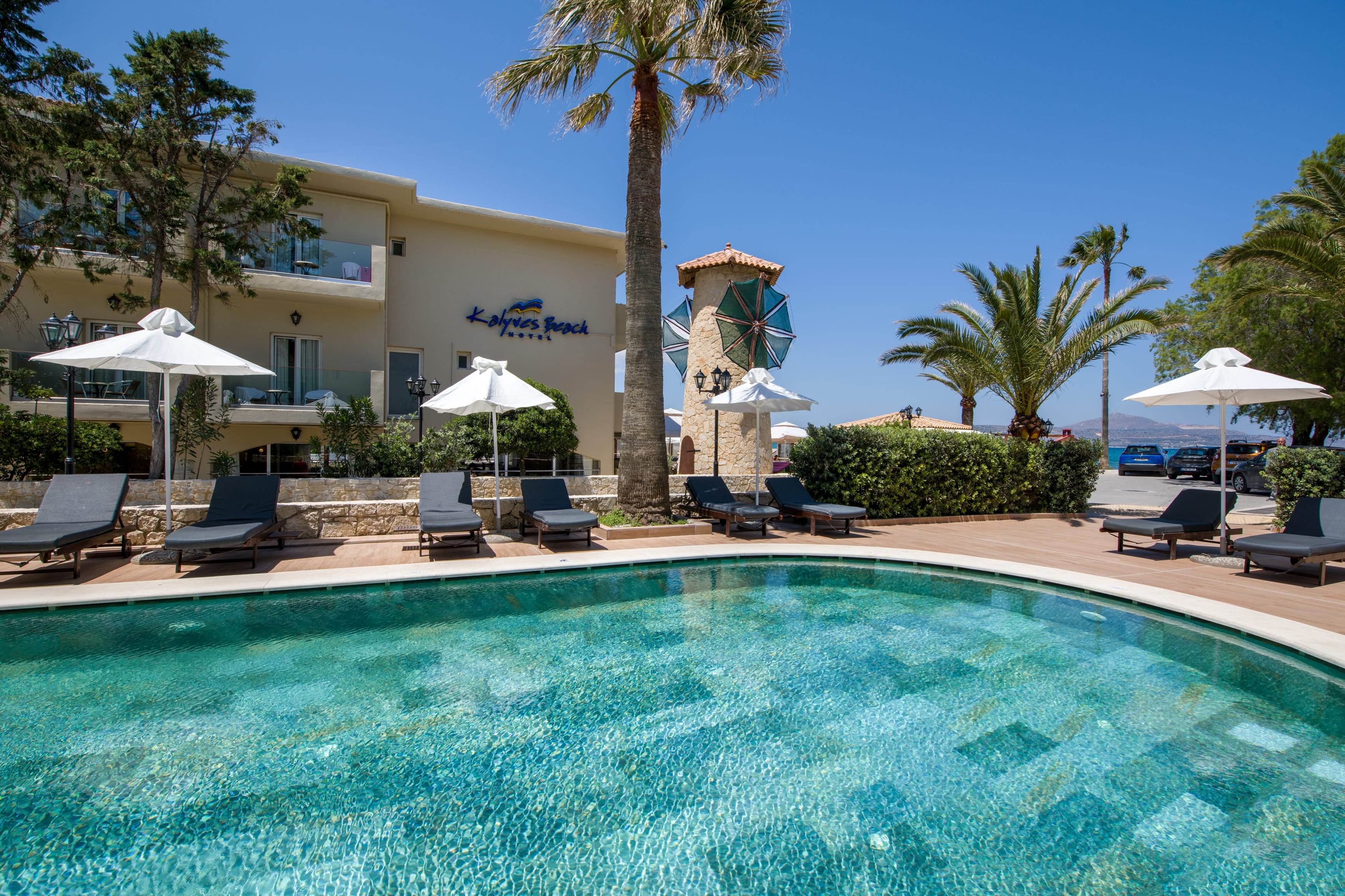 a pool with chairs and umbrellas by a building