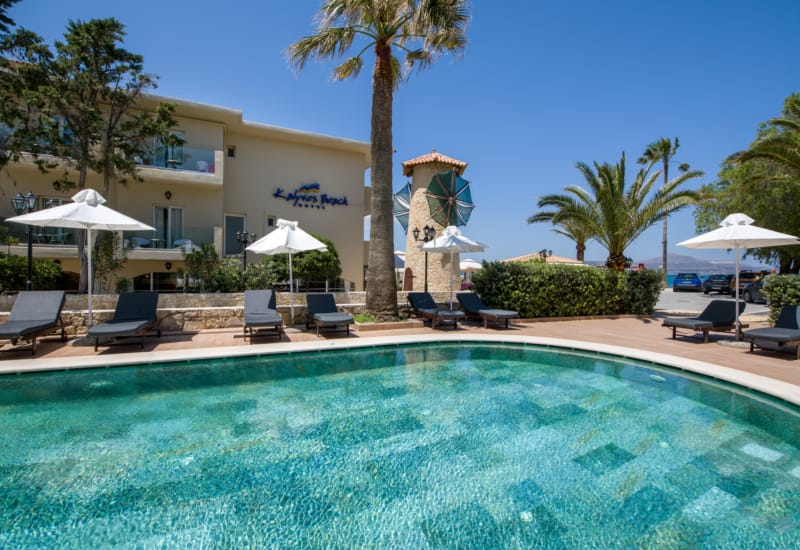 a pool with chairs and umbrellas by a building