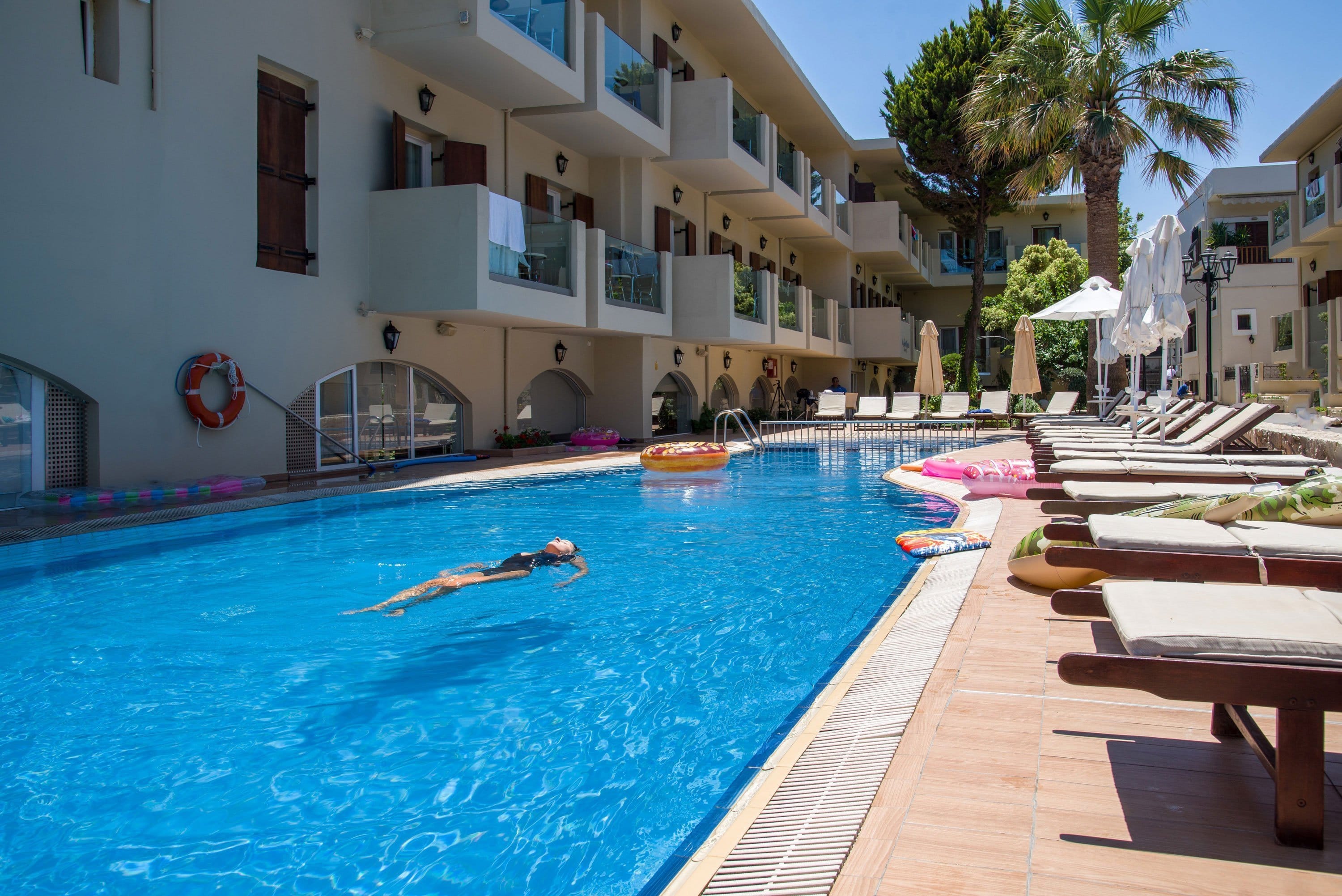 a swimming pool with lounge chairs and tables next to it
